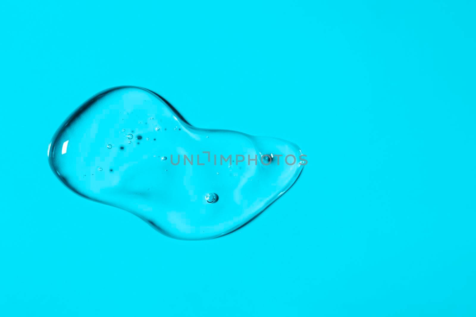 Clear liquid gel smear isolated on light blue background. Top view. Body and face care spa cosmetic concept. Transparent serum or hyaluronic acid texture. Banner with copy space.