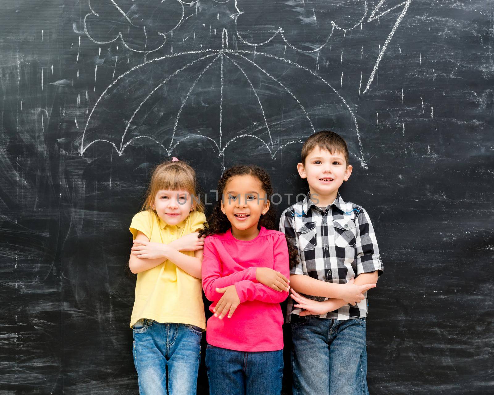 three funny children standing under drawn on blackboard umbrella