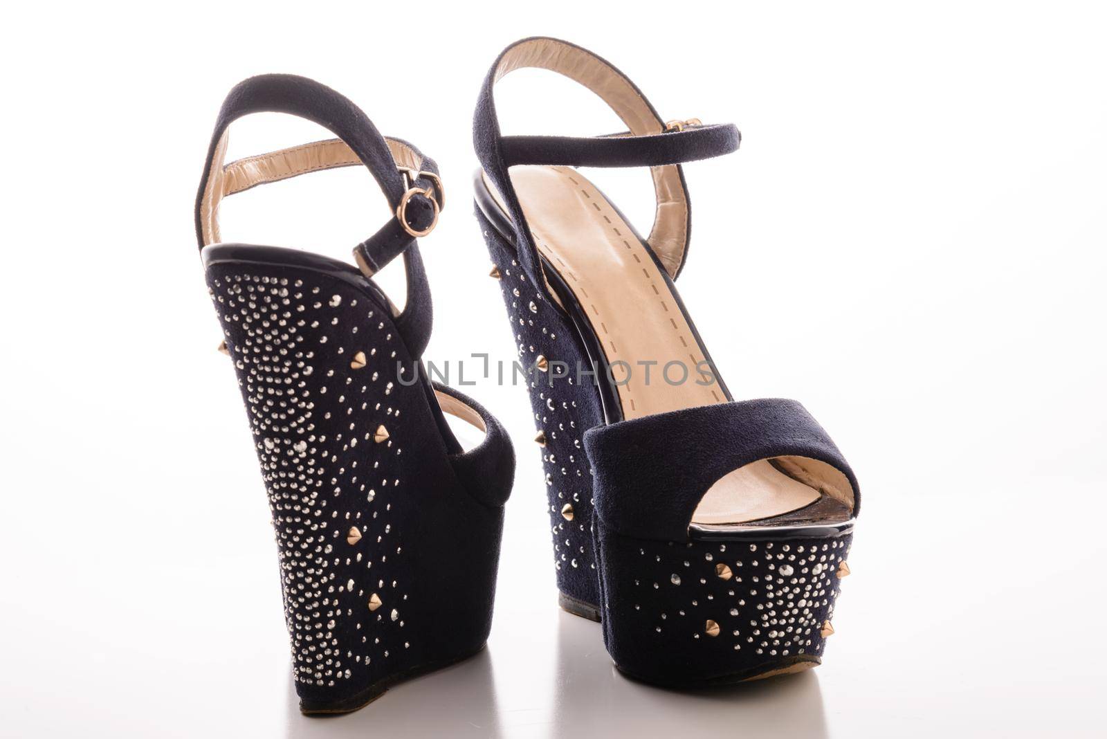 Stylish women&#39;s blue sandals with high heels with studs on a white background.