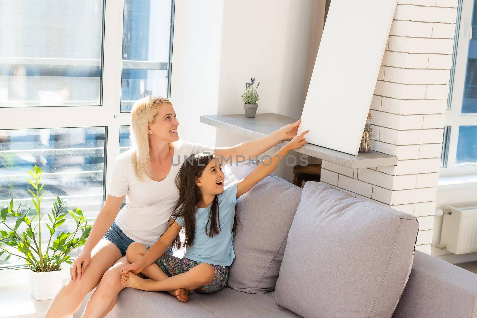 mother and daughter hold photo canvas at home