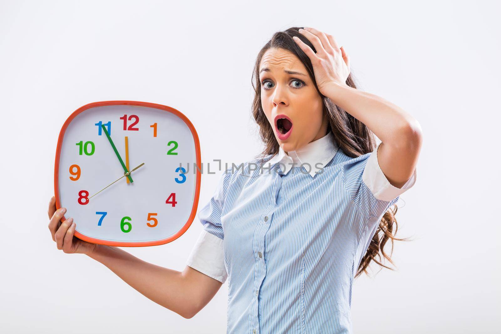 Image of businesswoman in panic holding clock on gray background.