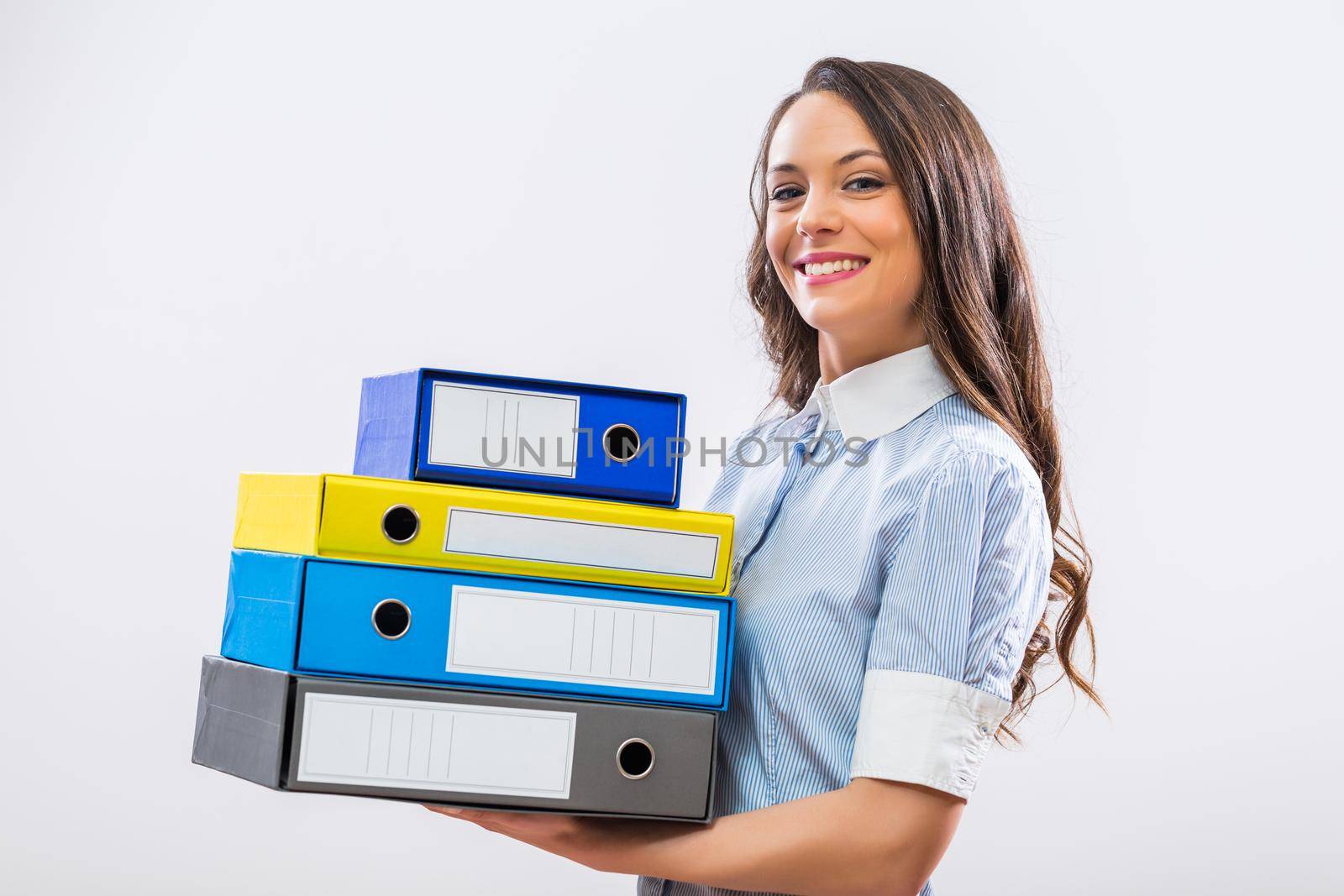 Portrait of happy businesswoman holding office archives on gray background.