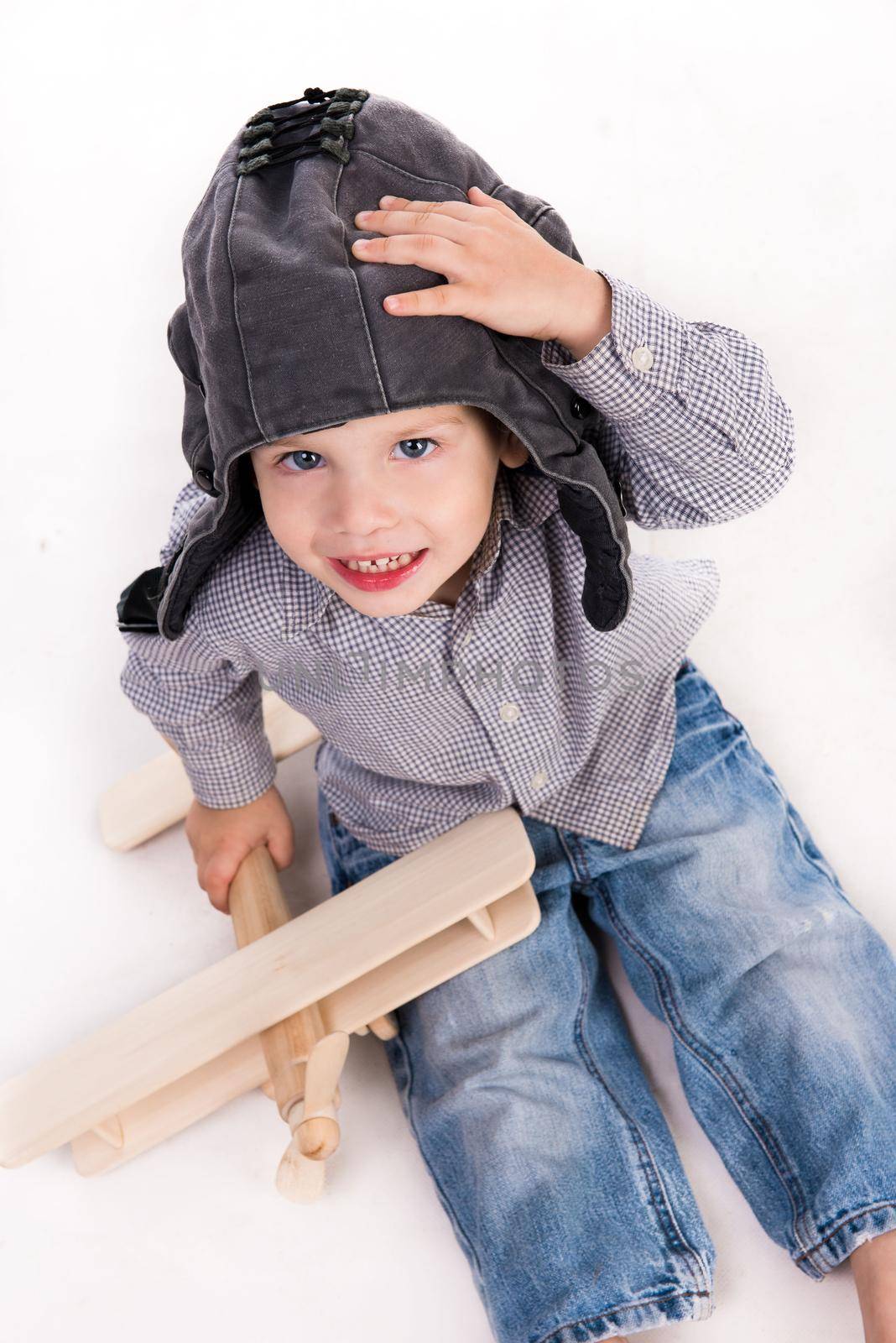 little boy with pilot hat playing toy plane isolated on white background