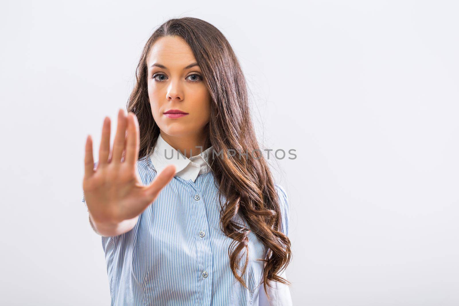 Image of serious businesswoman showing stop sign on gray background.