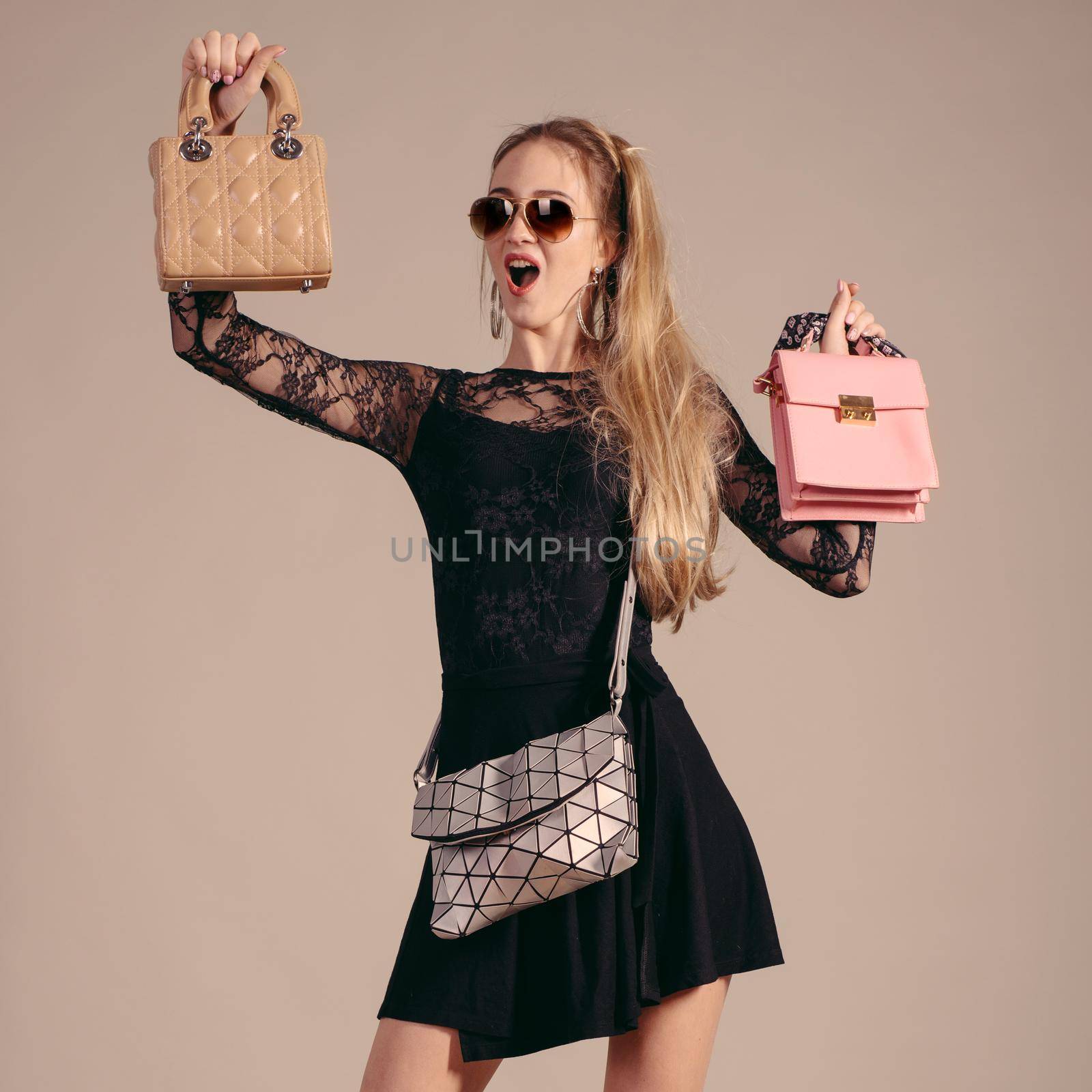 Young woman posing in black dress and sunglasses with three hand bag. by zartarn