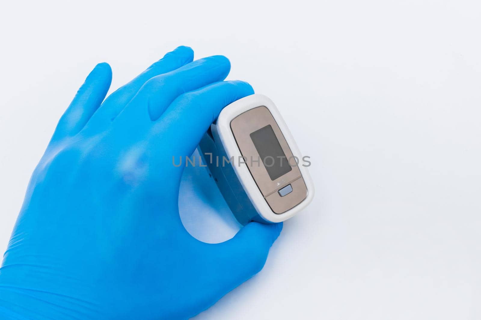 Doctor hand in protective medical gloves holding fingertip pulse oximeter on a white background, closeup.