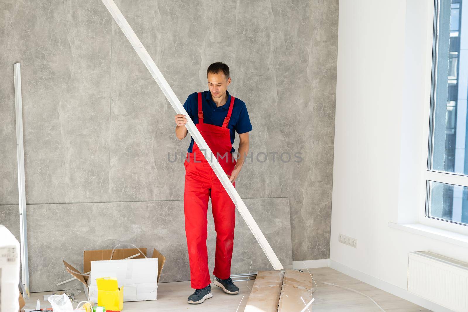 Rear back behind view photo of unrecognizable repairman master using rule to measure the required width of drywall and put label mark