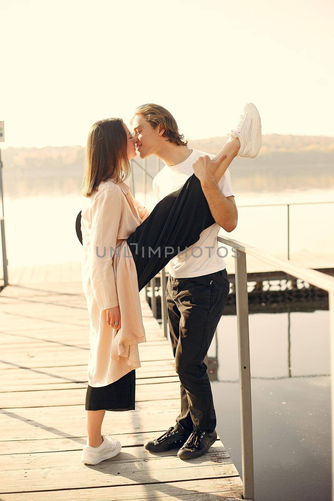Couple by the water. Guy in a white t-shirt. Pair on a sunset background.