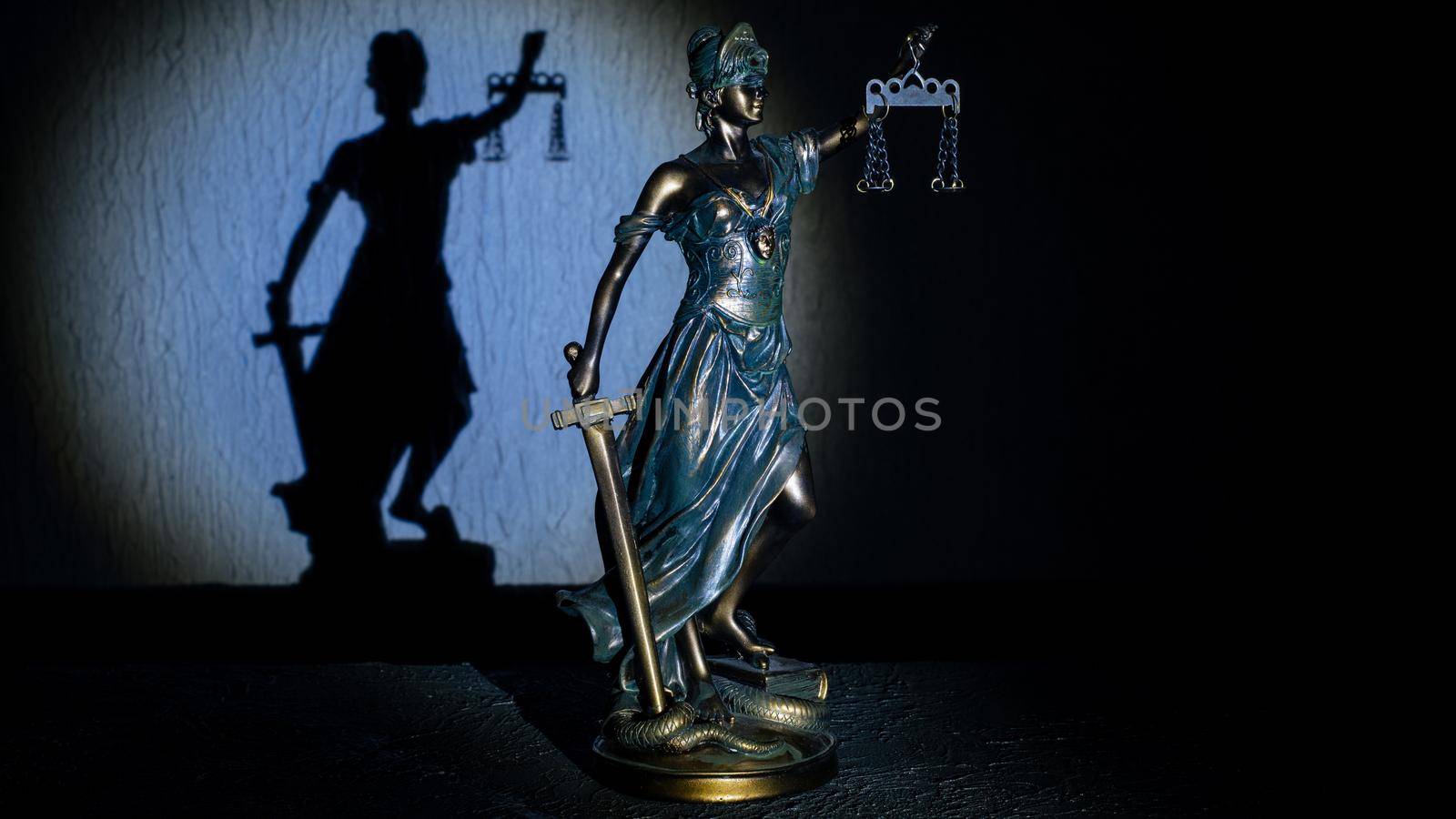 Themis statuette stands on the old vintage stone table. Picture taken with a light brush - Image
