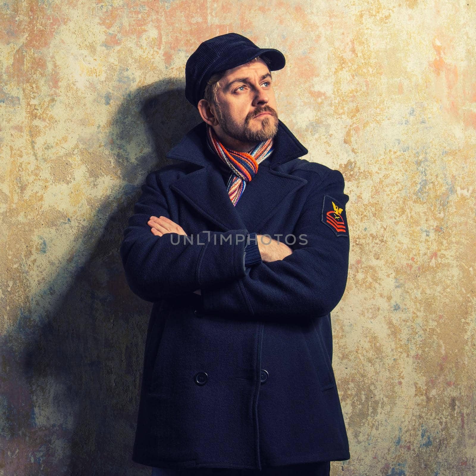 image of a caucasian man with grungy blond hair dressed warmly in a stylish black trench coat and a funky hat and scarf for the cold winter