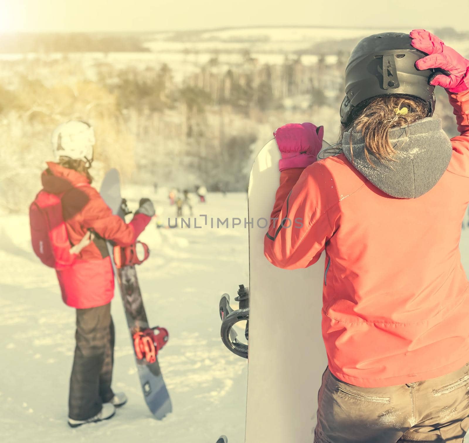 people in ski suit holding snowboards on a snowhill view from back