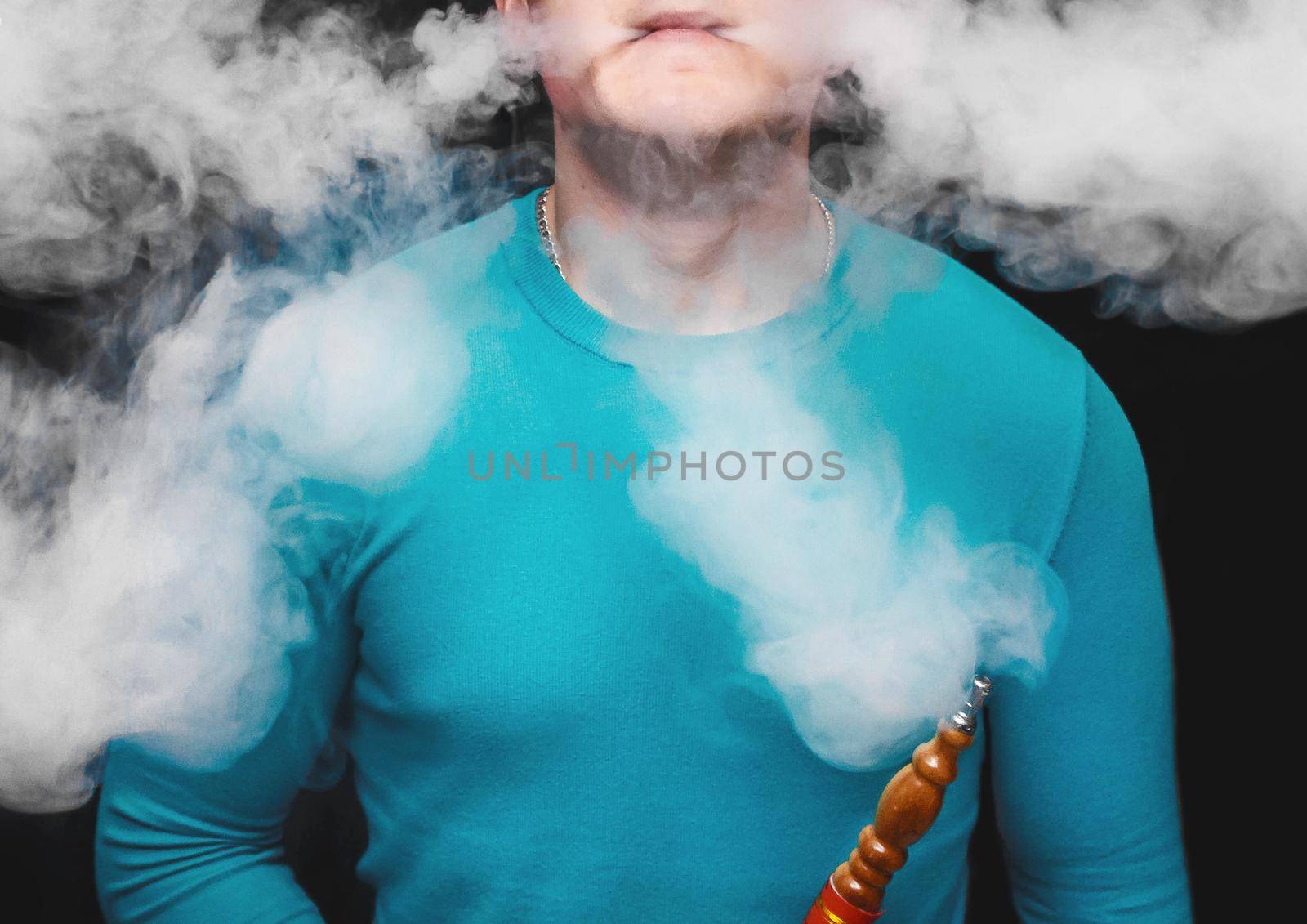 An adult guy smokes a hookah and makes a lot of white smoke, close-up.