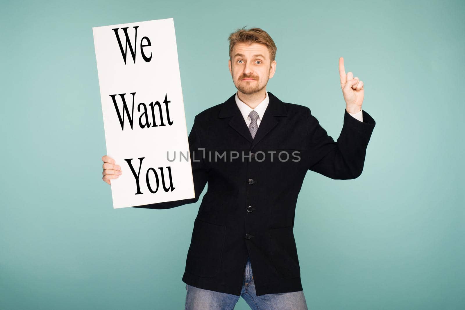 Happy smiling young business man showing signboard with sign We Want You, on blue background