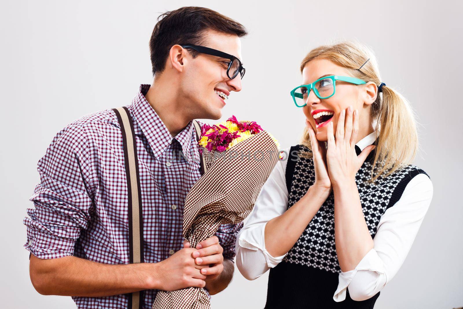 Romantic nerdy man is giving flowers to his nerdy lady.