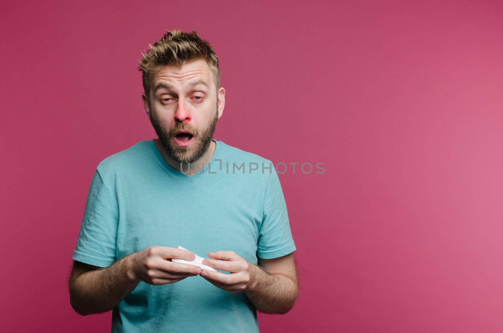 studio picture from a young man with handkerchief going to sneeze. Sick guy isolated has runny nose. man makes a cure for the common cold from the air conditioner