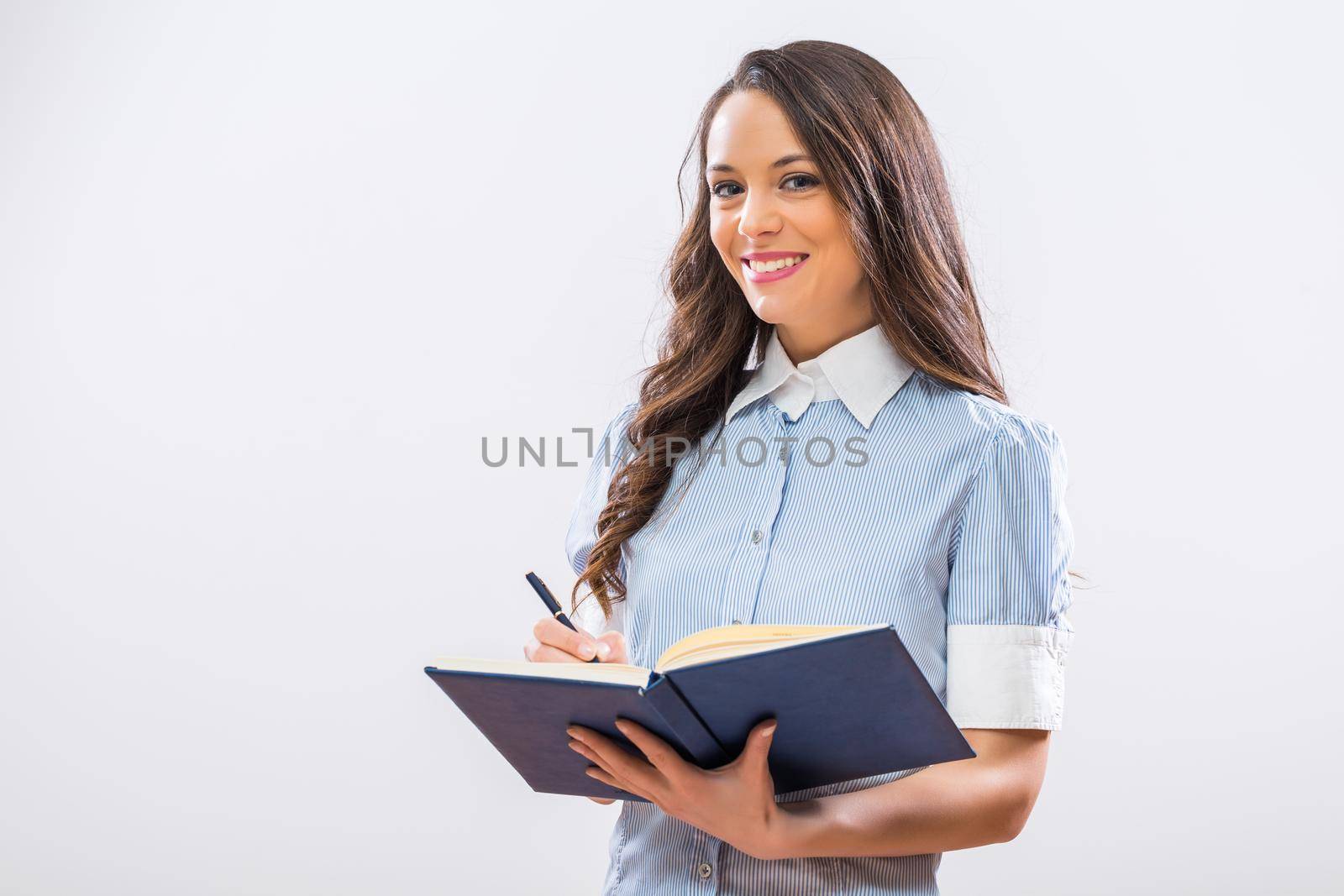 Portrait of beautiful businesswoman holding note pad on gray background.