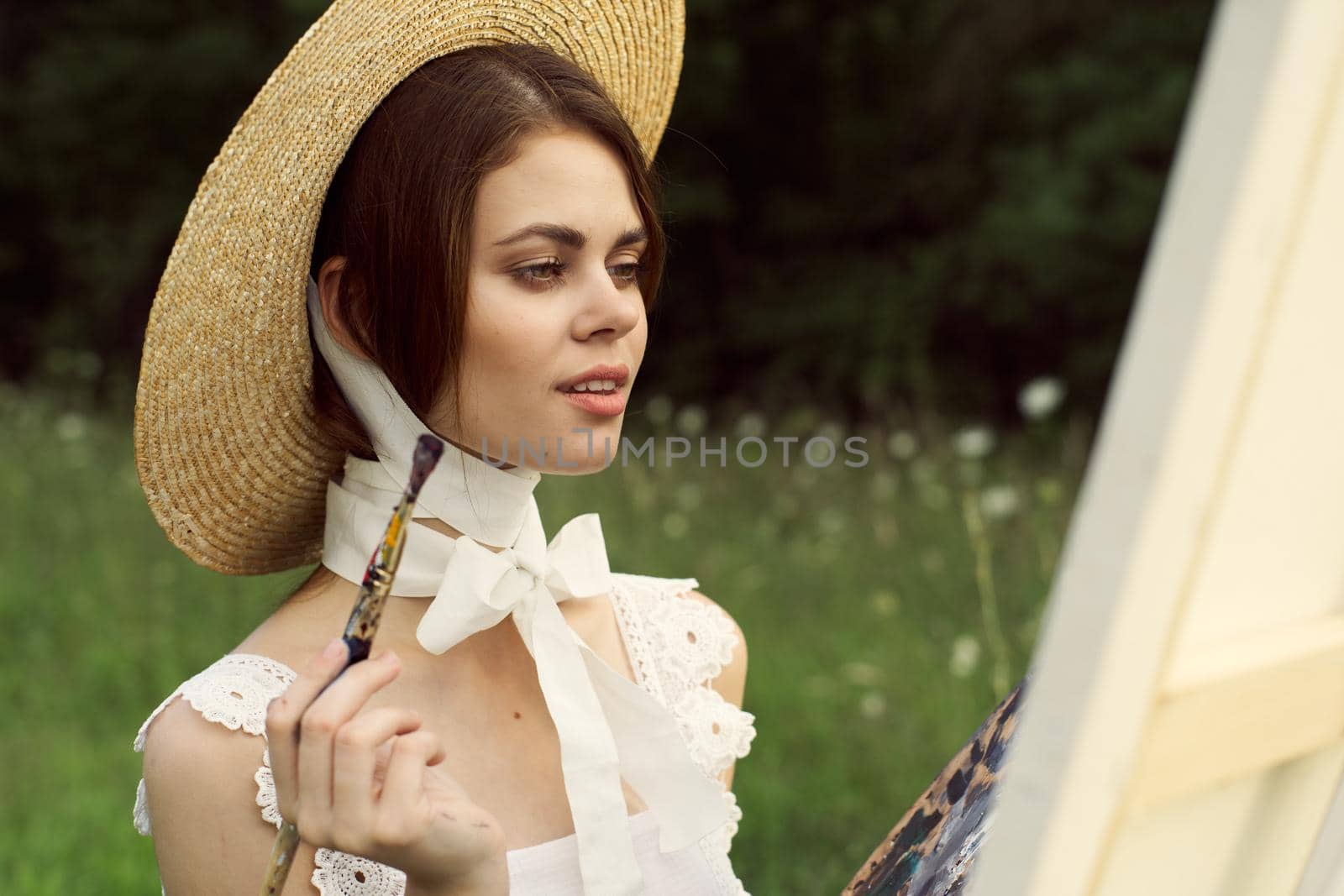 Woman in white dress outdoors artist drawing easel. High quality photo