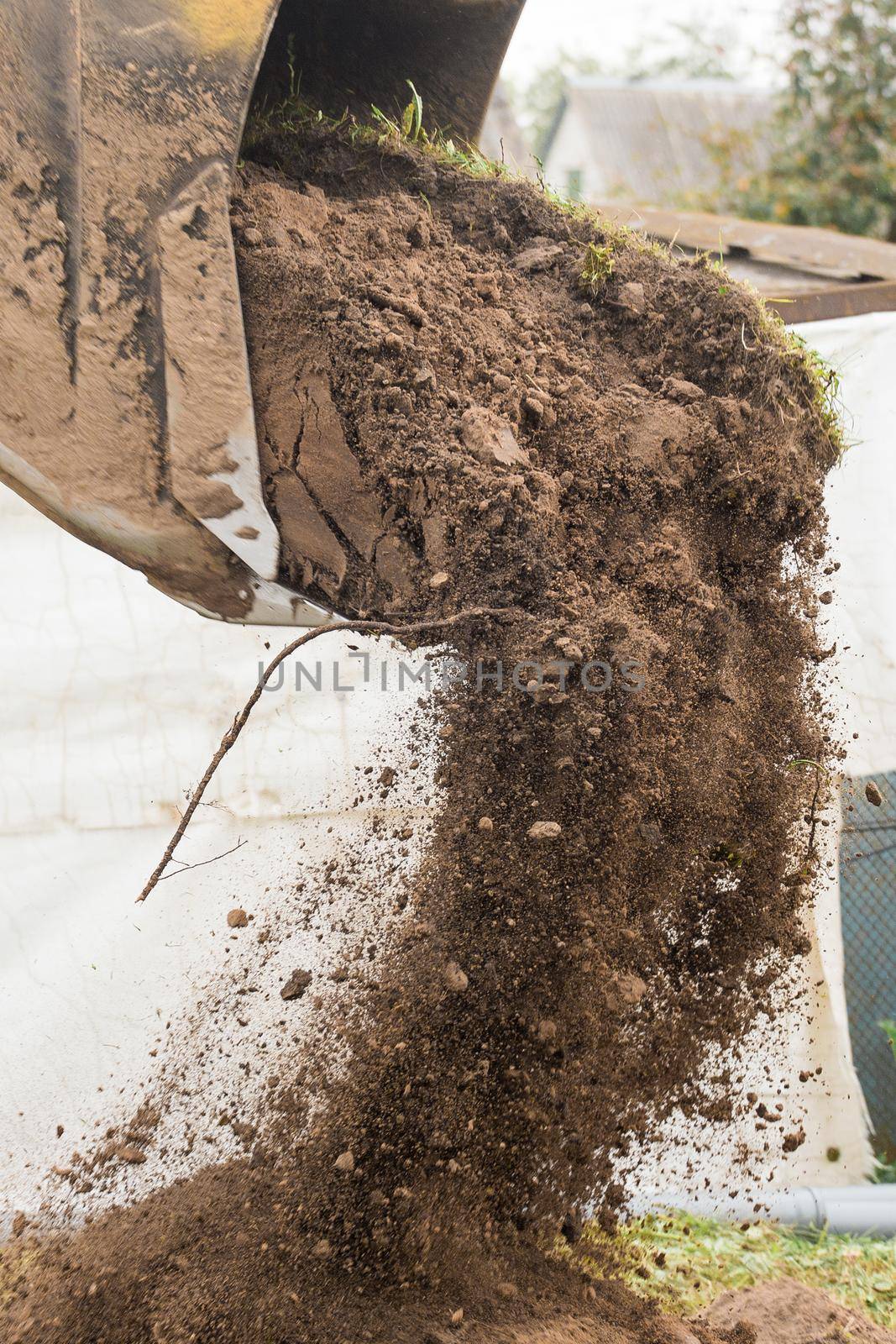 A bulldozer pours out a bucket of land on a construction site close-up. Excavation industrial work by AYDO8