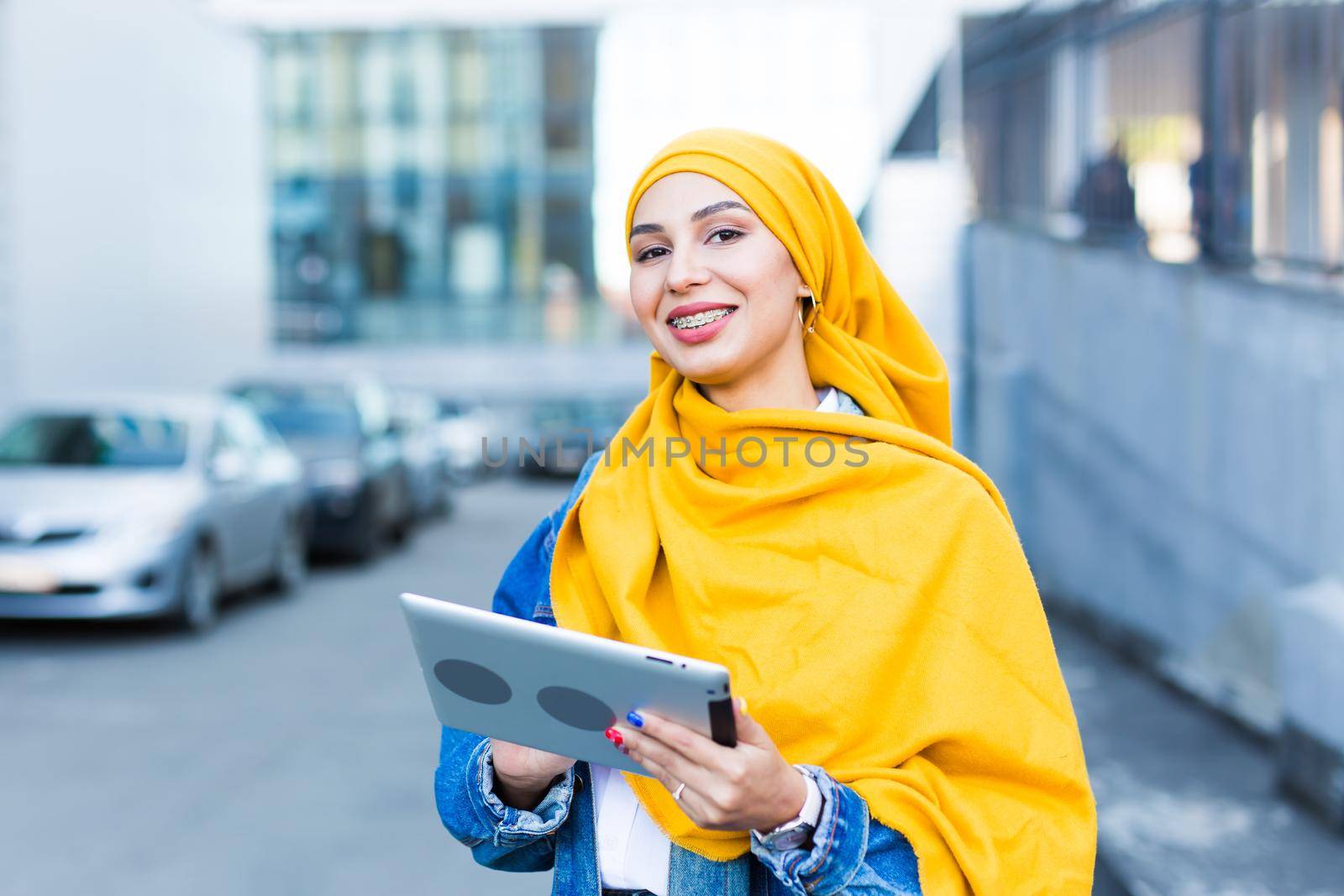 Arab woman student. Beautiful muslim female student wearing yellow hijab holding tablet