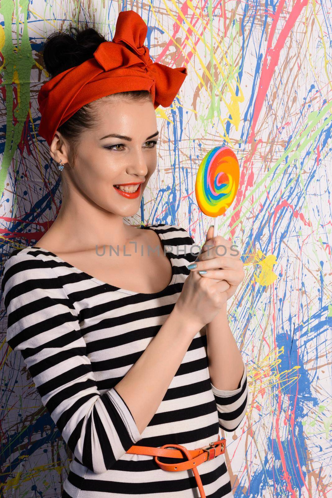 portrait of beautiful girl with big lollipop at wall with different color splash