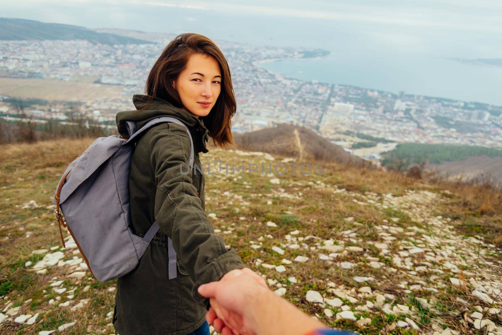 Traveler beautiful young woman holding man's hand and leading him on nature outdoor. Couple in love. Focus on woman