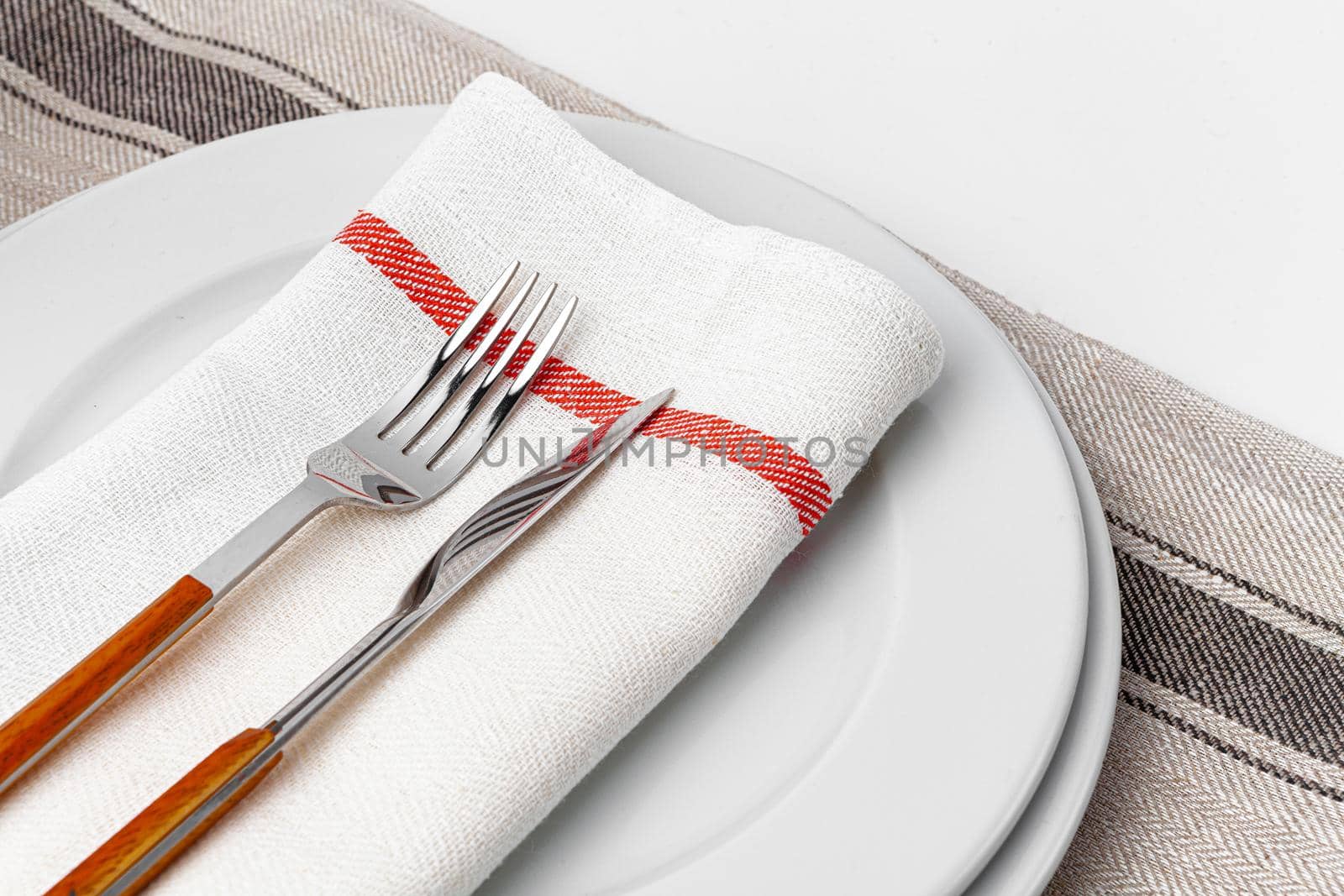 Fork, knife and plate on towel. Isolated on white background. Close up.