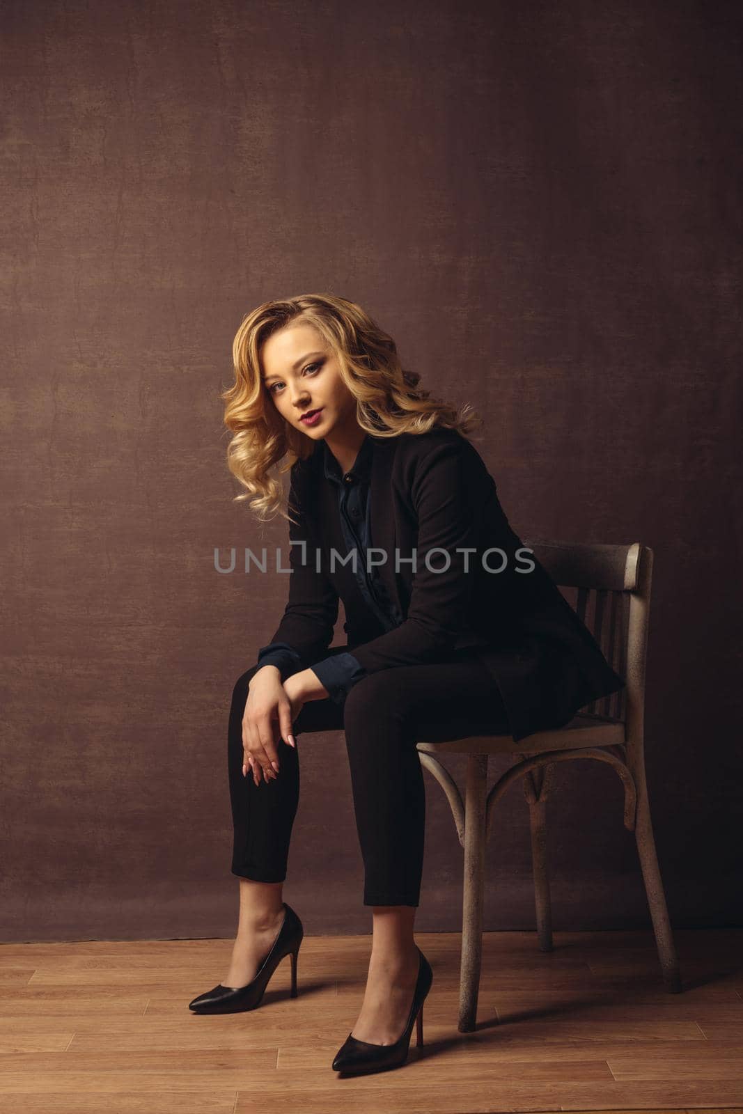Young confident businesswoman sitting on the chair on gray background by zartarn