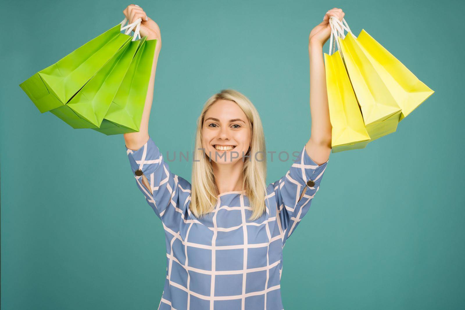 Happy girl in a checkered blouse holds shopping bags on blue background