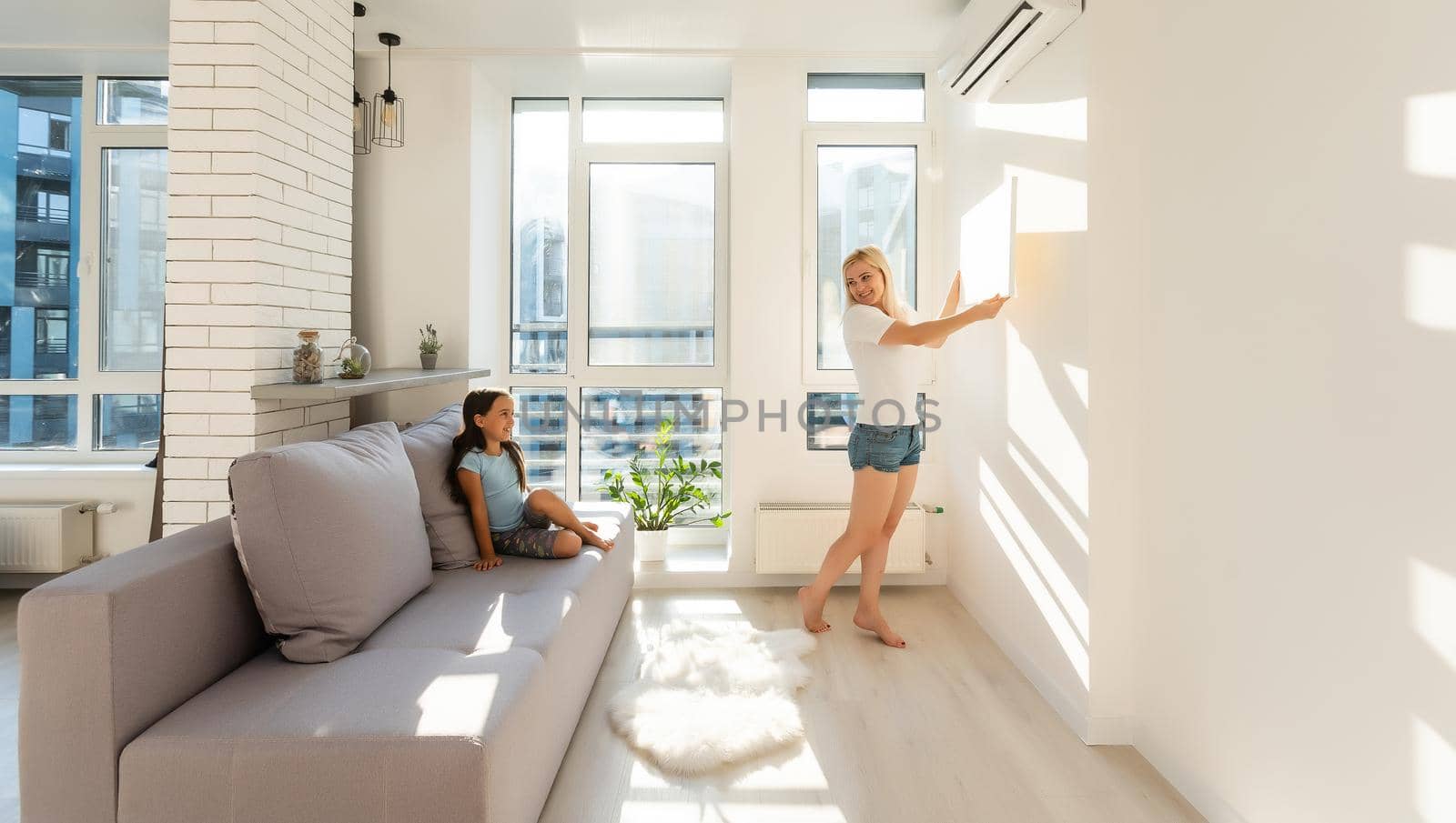 mother and daughter hangs a large photo canvas at home