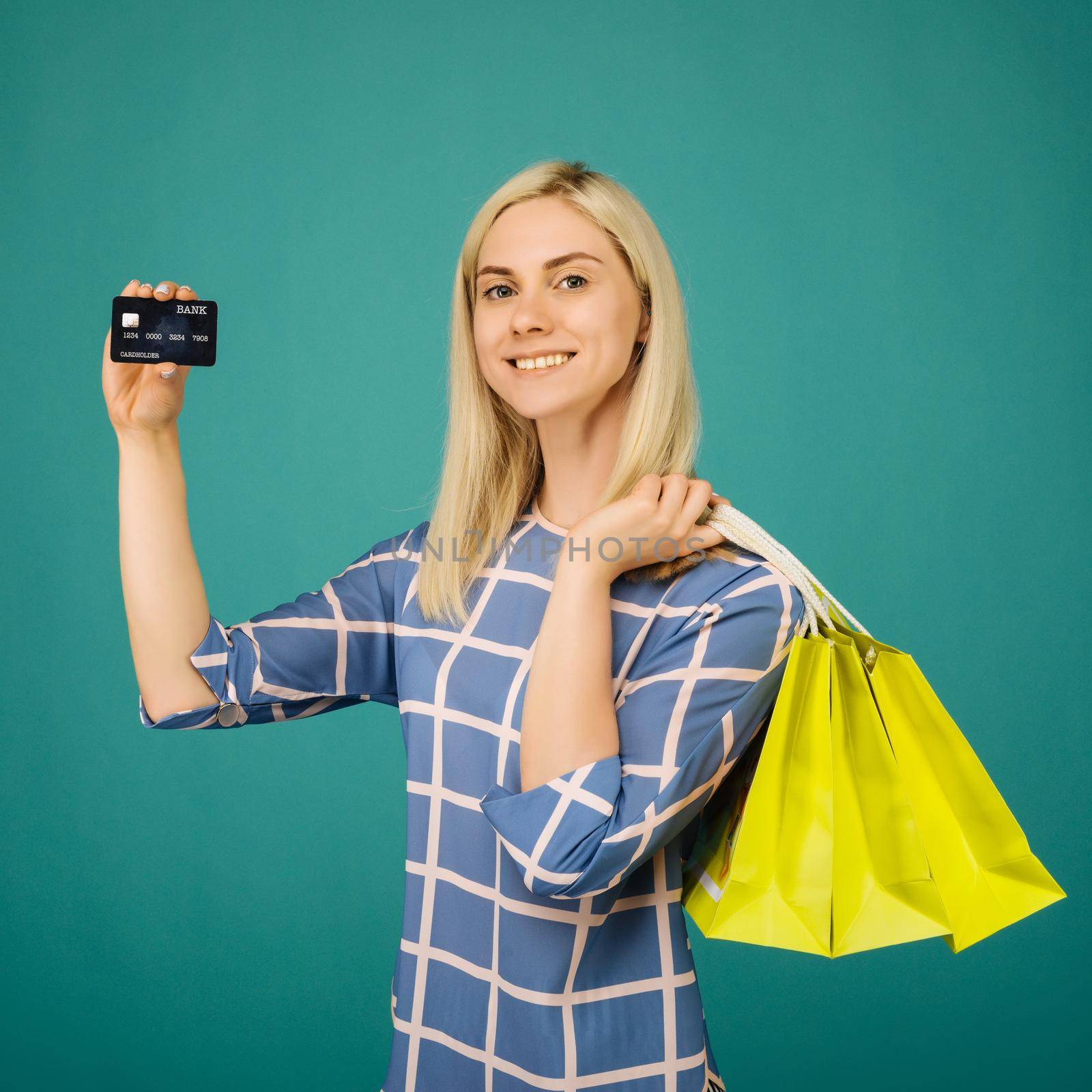 Happy girl in a checkered blouse holds credit card and shopping bags by zartarn
