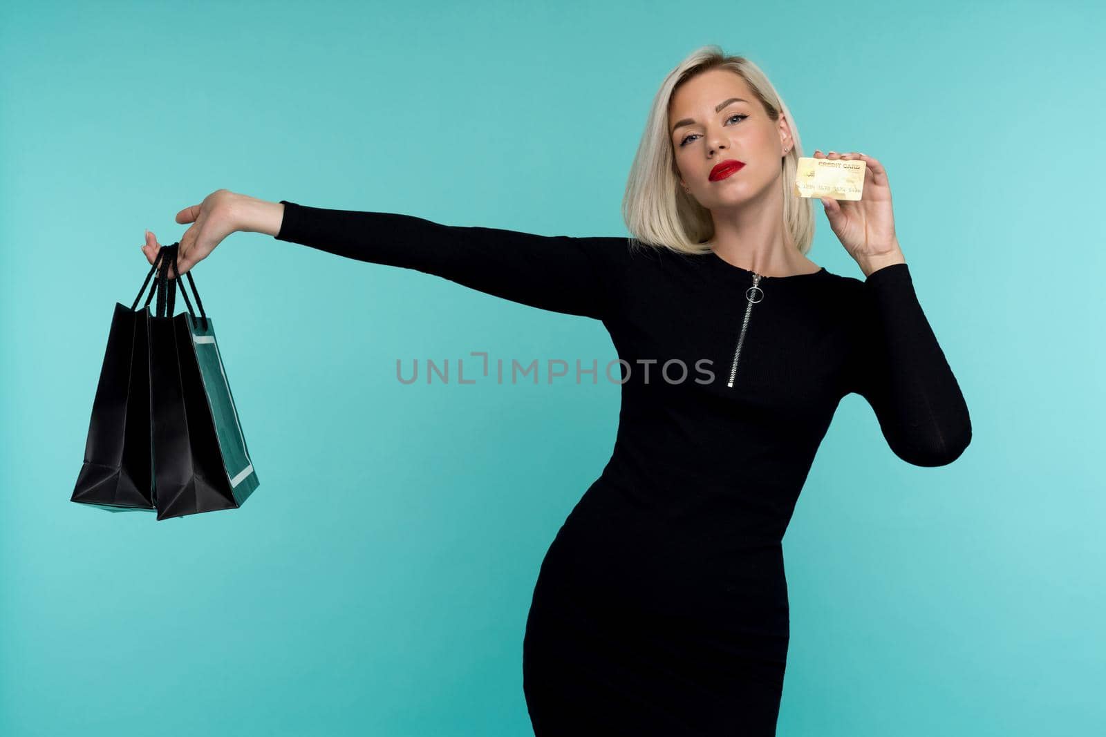 Image of a beautiful happy young blonde woman posing isolated over blue wall background holding shopping bags. by zartarn