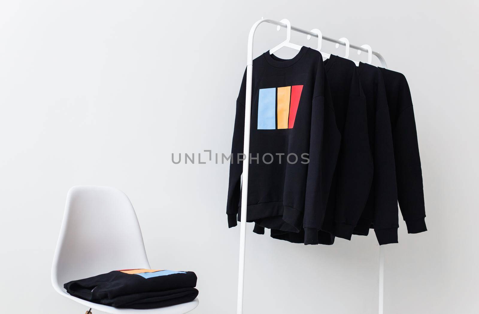 Sweatshirts and hoodies hanging on hangers in the store. Street fashion, unisex and youth wears. by Satura86