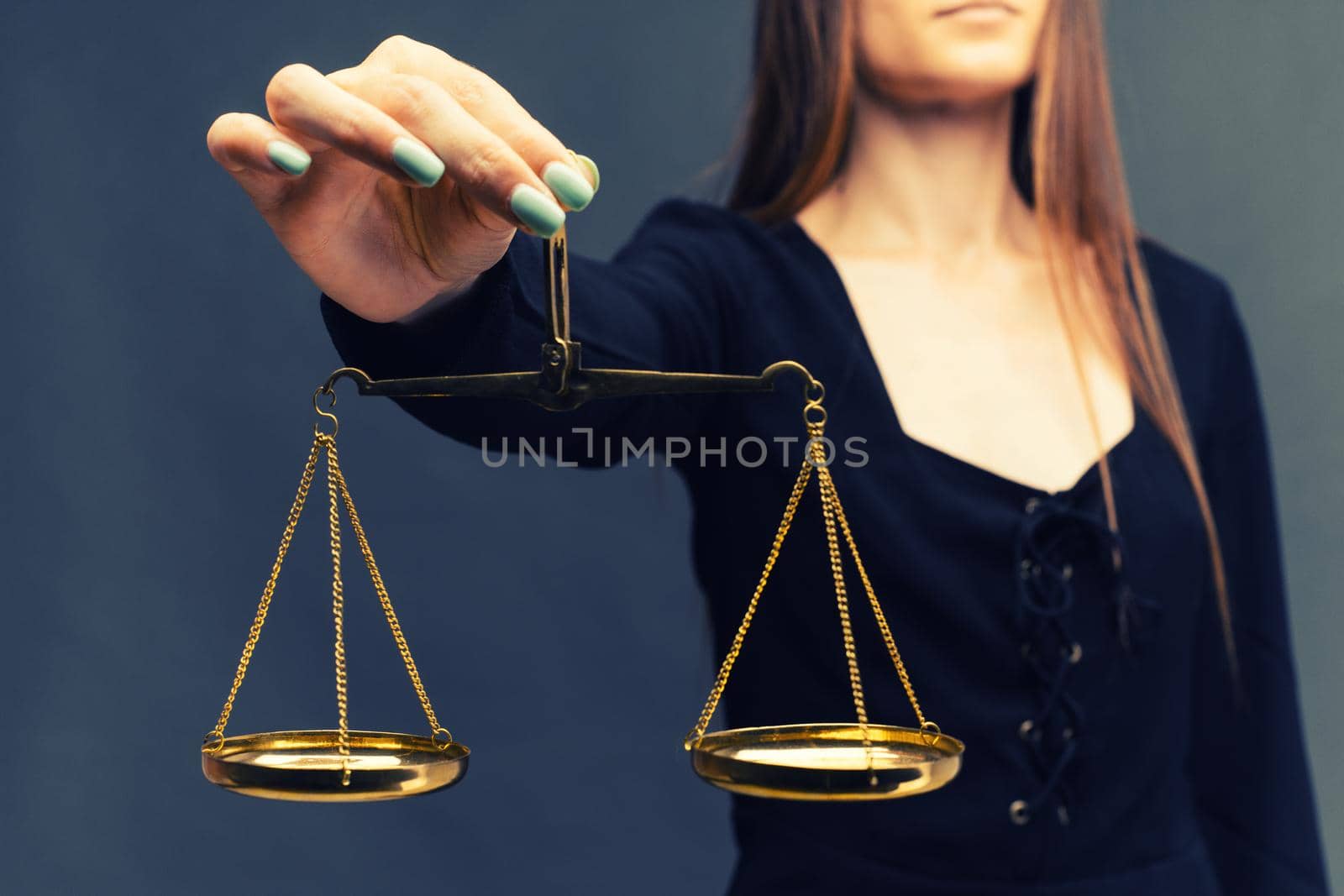 Serious woman holding the justice scale on dark background - image toned