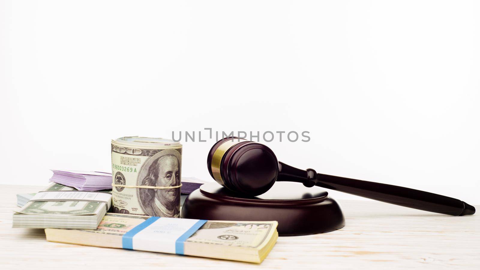 Judge's gavel and packs of dollars and euro banknotes on a white wooden table. The concept of growing national debt- image