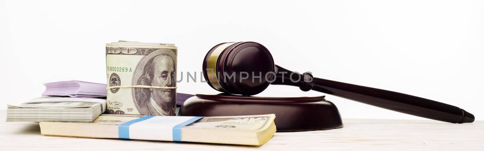 Judge's gavel and packs of dollars and euro banknotes on a white wooden table. The concept of growing national debt- image