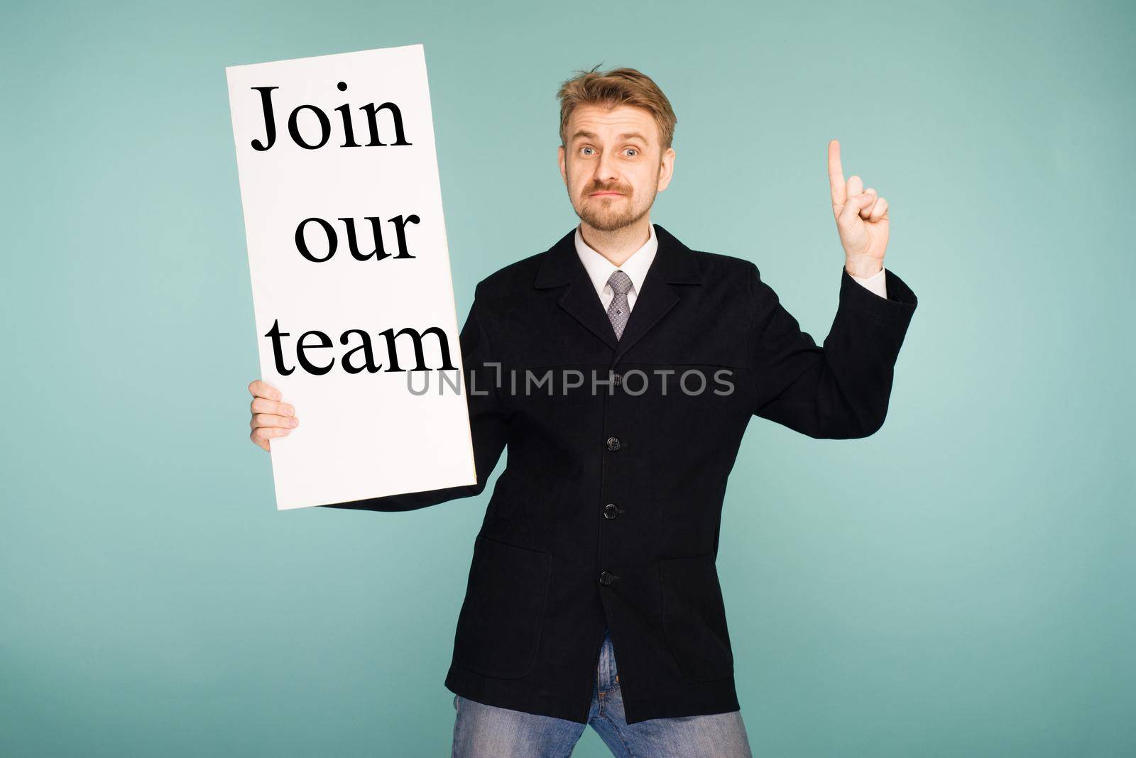 Happy smiling young business man showing signboard with sign Join Our Team, on blue background