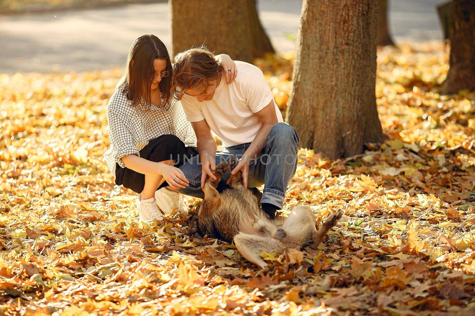 Couple in a park. Guy in a white t-shirt. Golden autumn. People with dog.