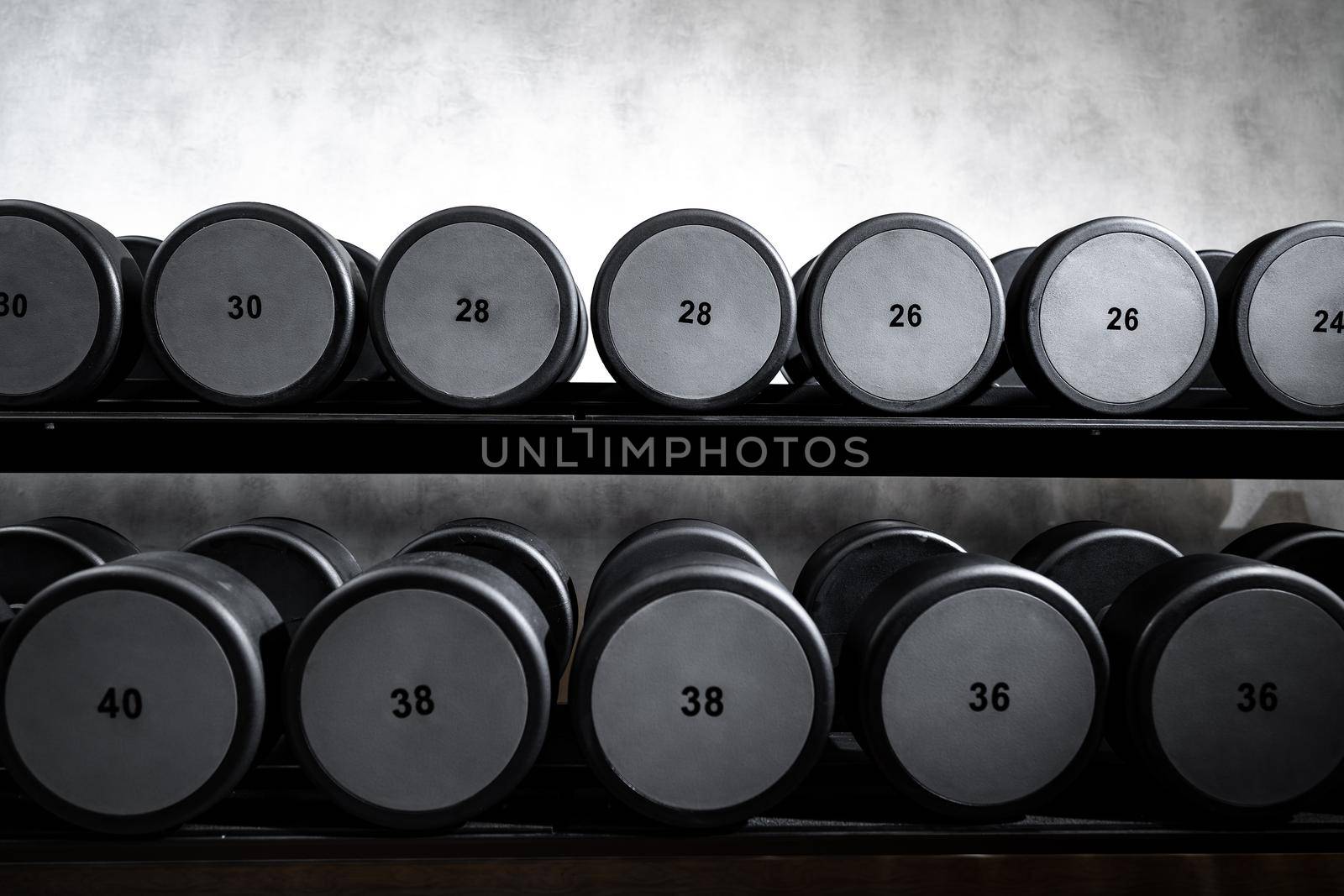 Rows of metal dumbbells on rack for bodybuilding in a gym