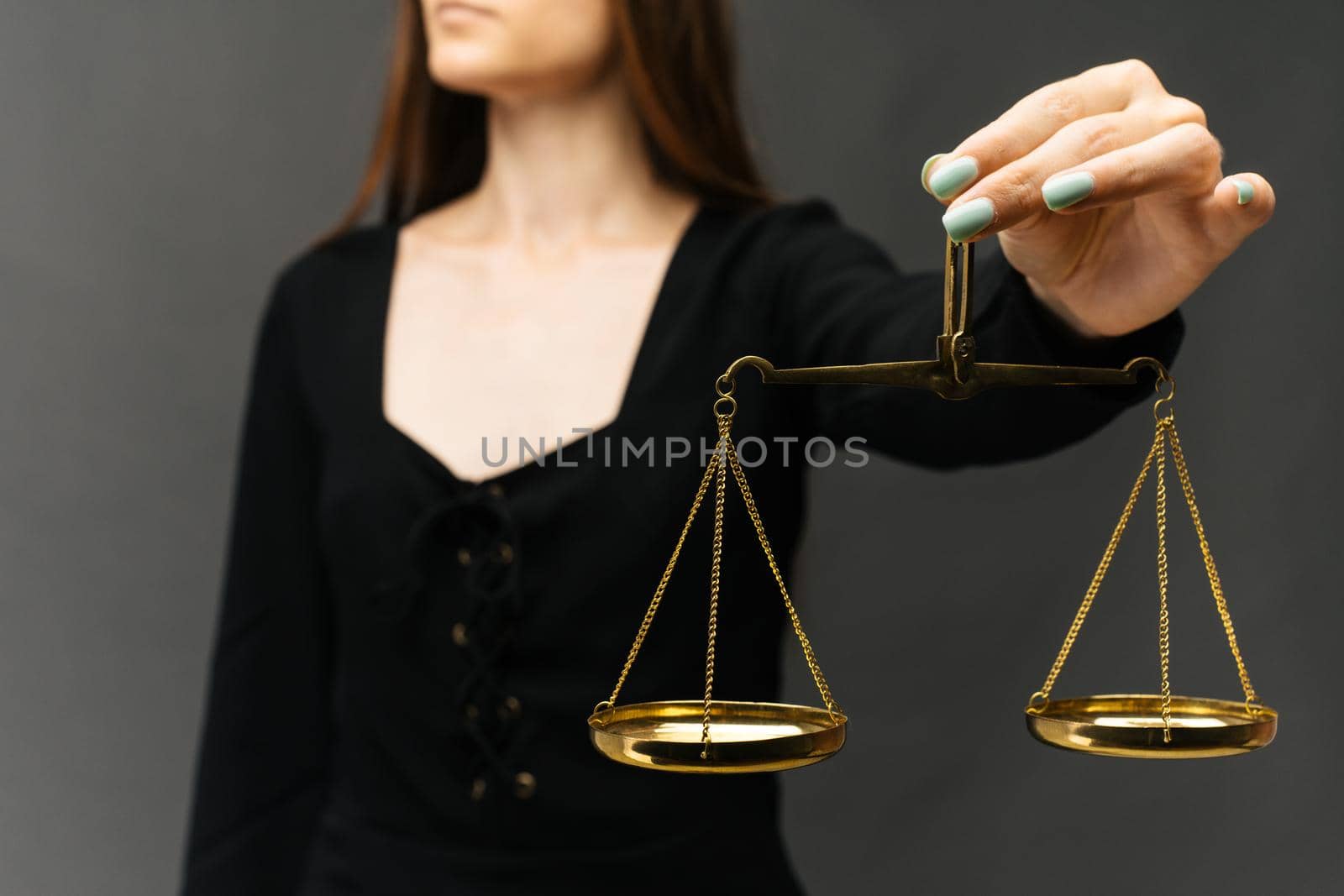Serious woman holding the justice scale on dark background - image