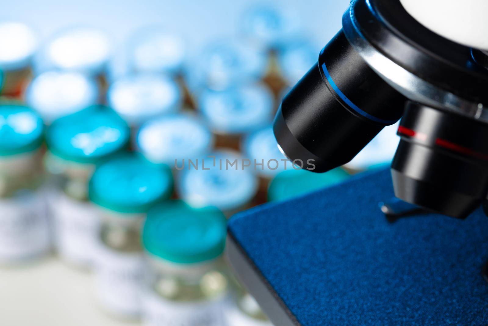 Medical vial with medication near microscope close up photo