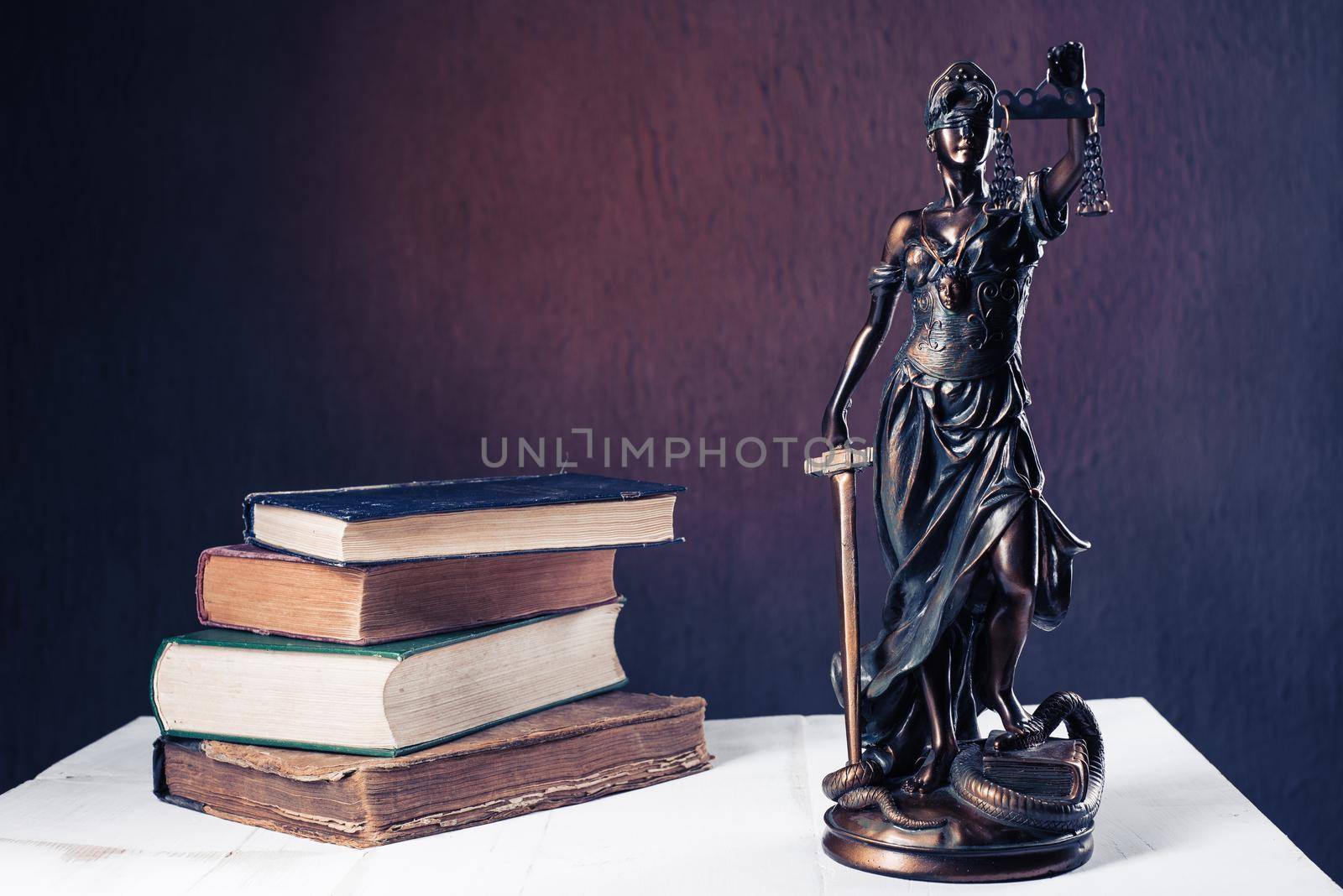 Themis figurine stands on a white wooden table next to a stack of old books. Scales Law Lawyer Business Concept. - Image