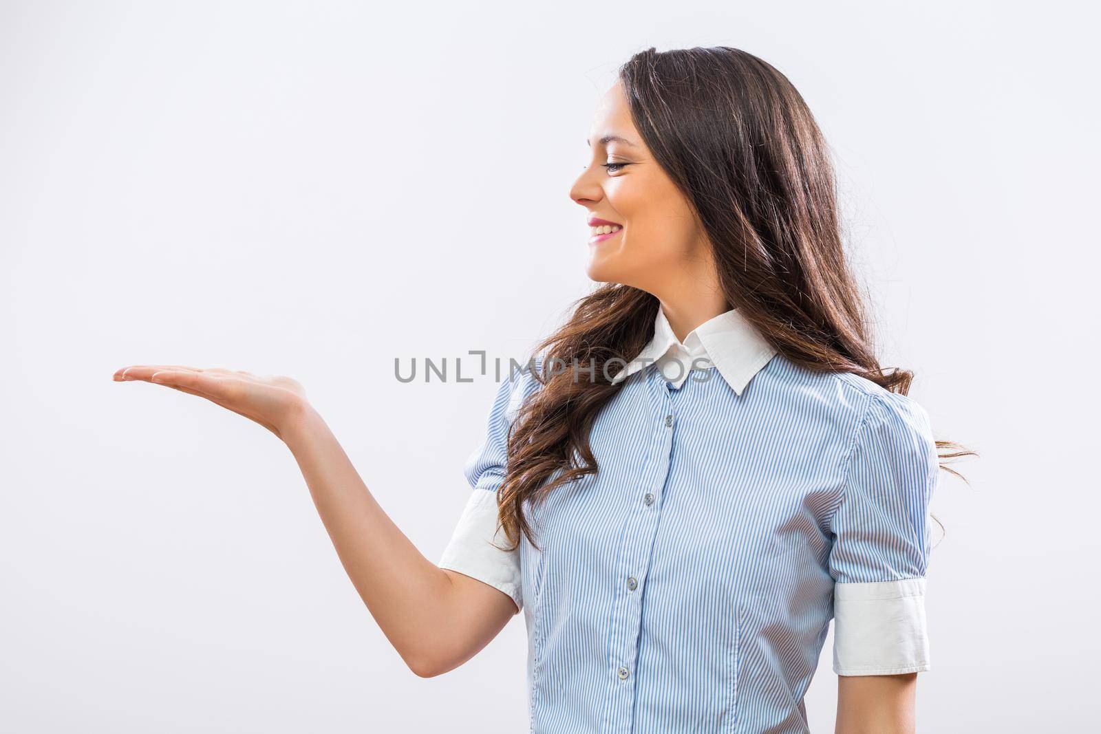 Image of beautiful businesswoman showing palm of hand on gray background.