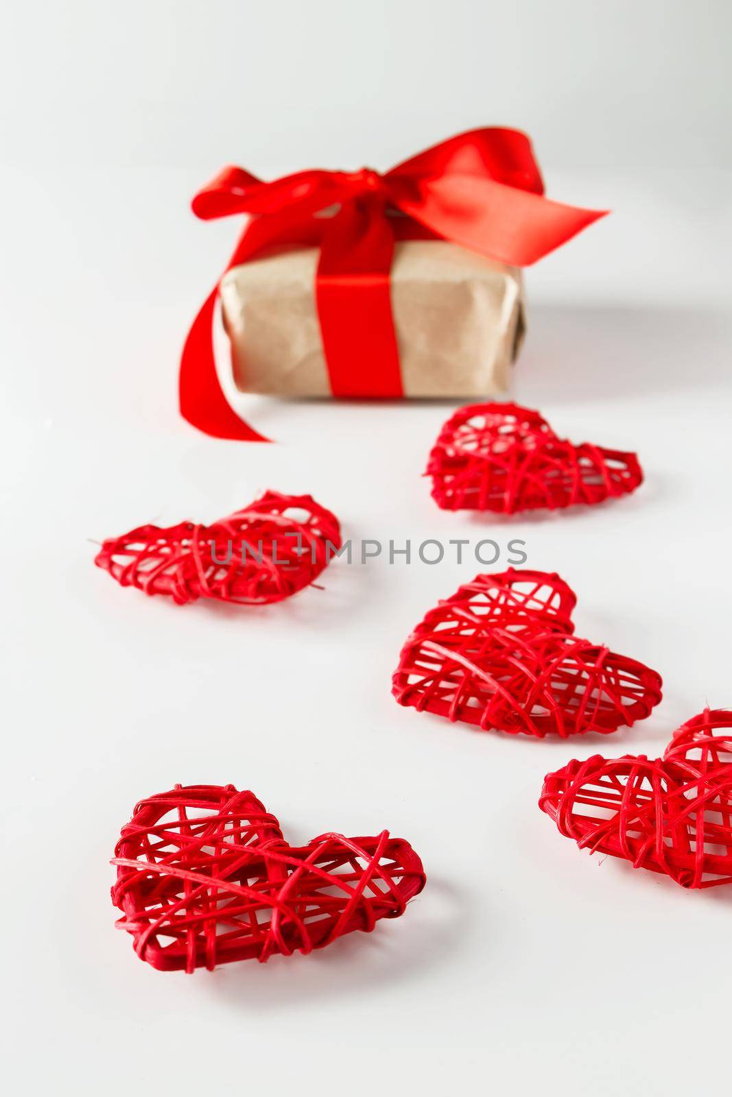 Valentine's day gift and red hearts on a white background. Valentine's Day gift on a background of red hearts from twigs of twigs, vertical photo