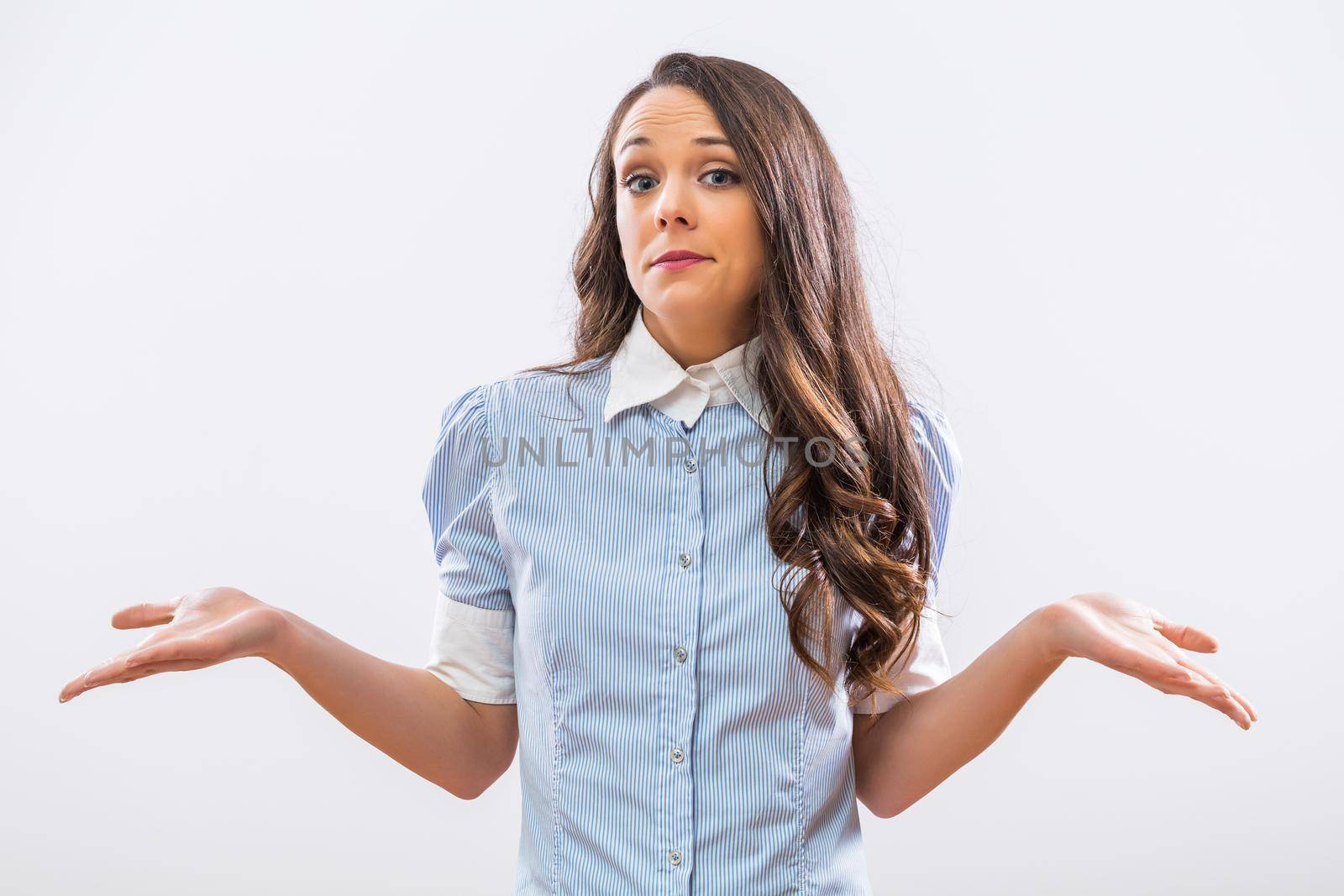 Image of confused businesswoman shrugging on gray background.