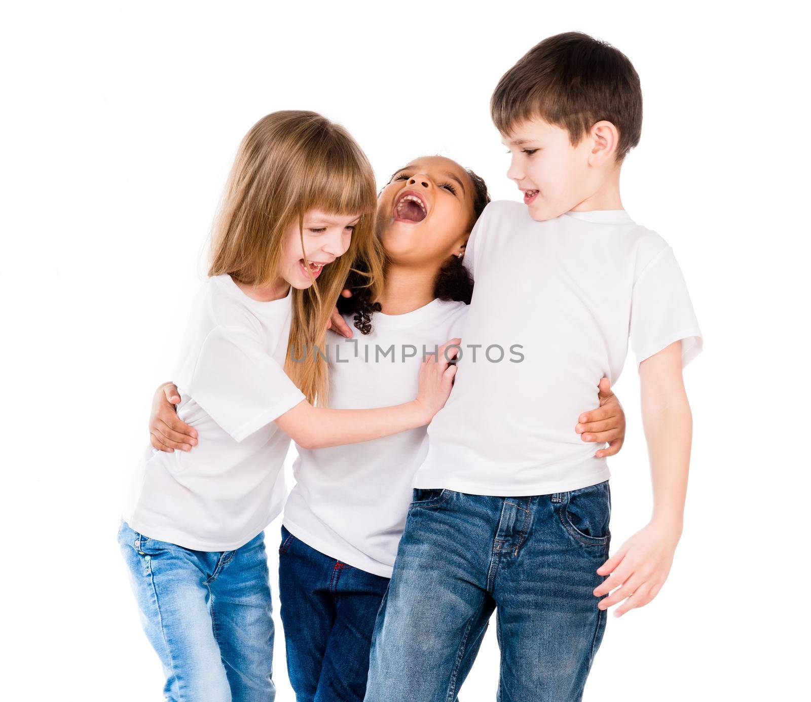 three trendy children with different complexion laugh embracing each other isolated on white background