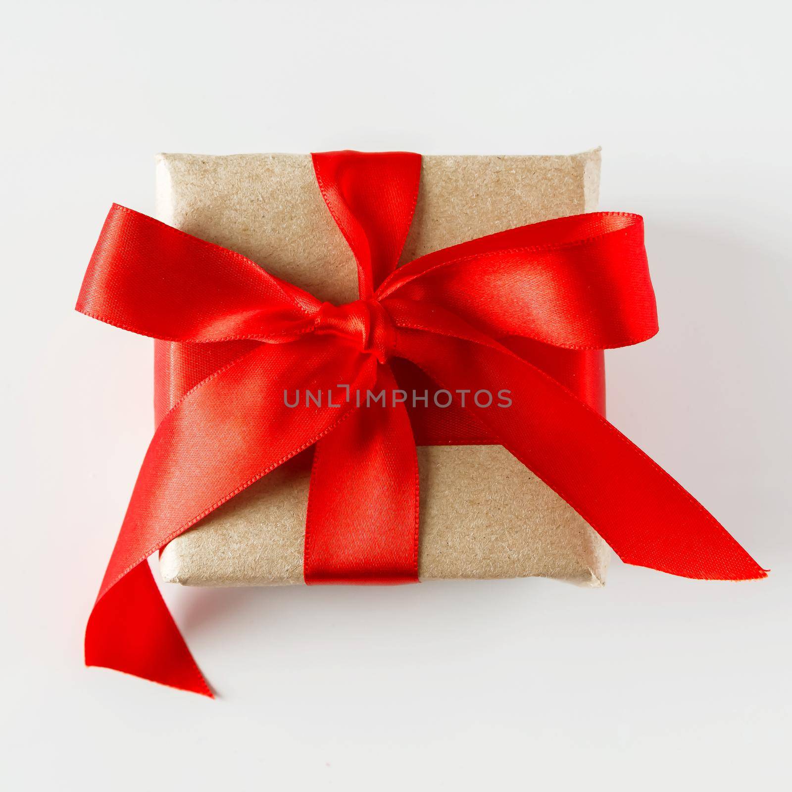 Valentine's day gift and red hearts on a white background. Valentine's day gift in craft paper with a red ribbon on a white background