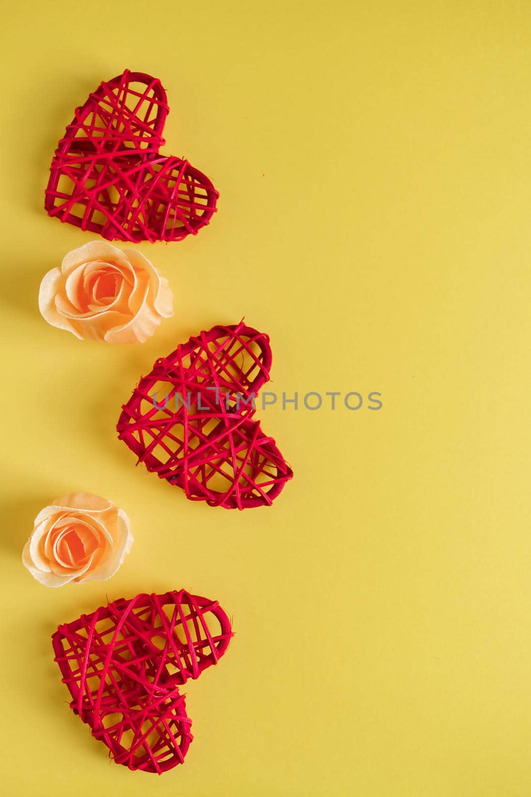Red hearts and flowers on a yellow background. Greeting card design for Valentine's Day. Place for text, vertical photo.
