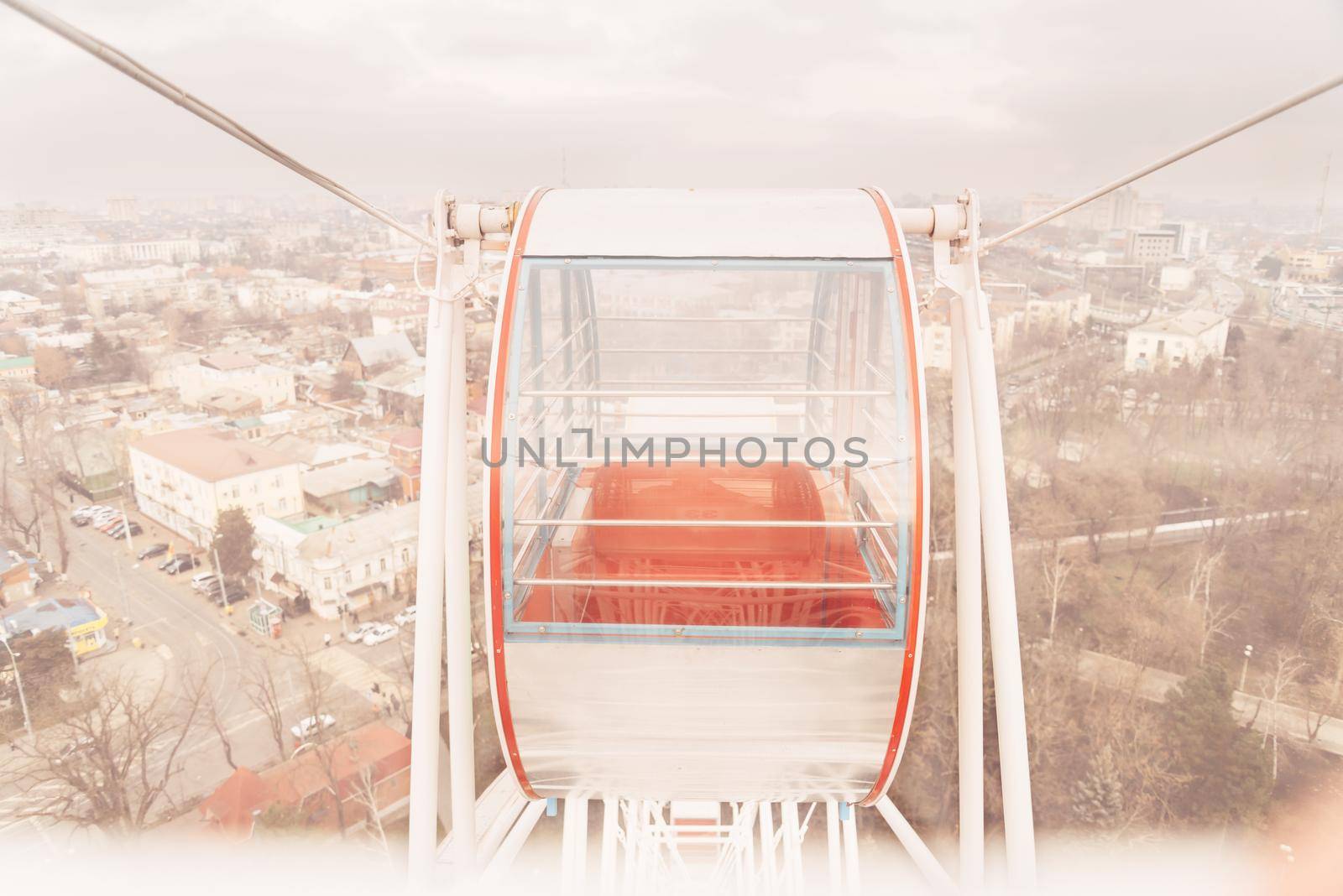 Closed cabin with red chair of ferris wheel on background of city, close-up image