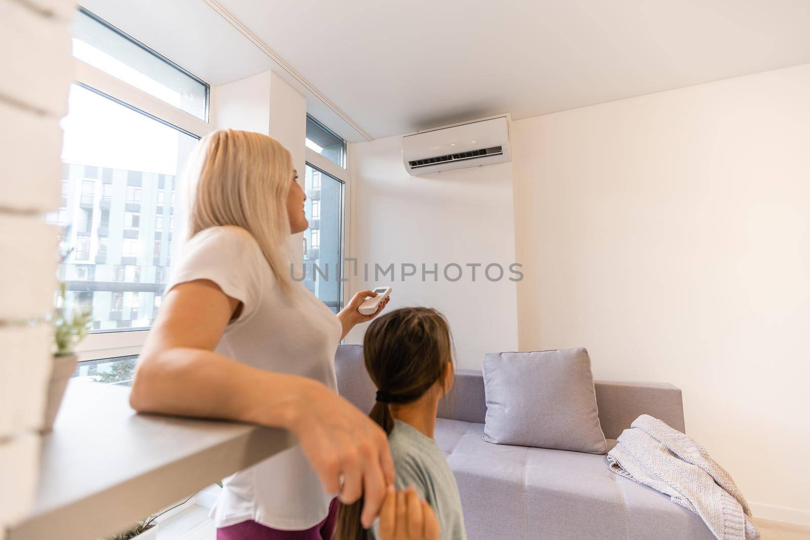 Mother in sportswear with daughter standing near the air conditioning by Andelov13