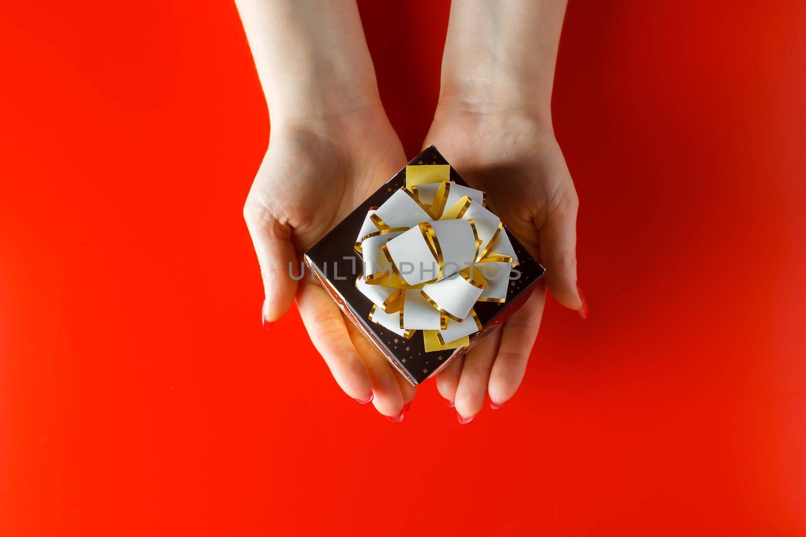 Gift with a red ribbon in hands on a white background by Statuska